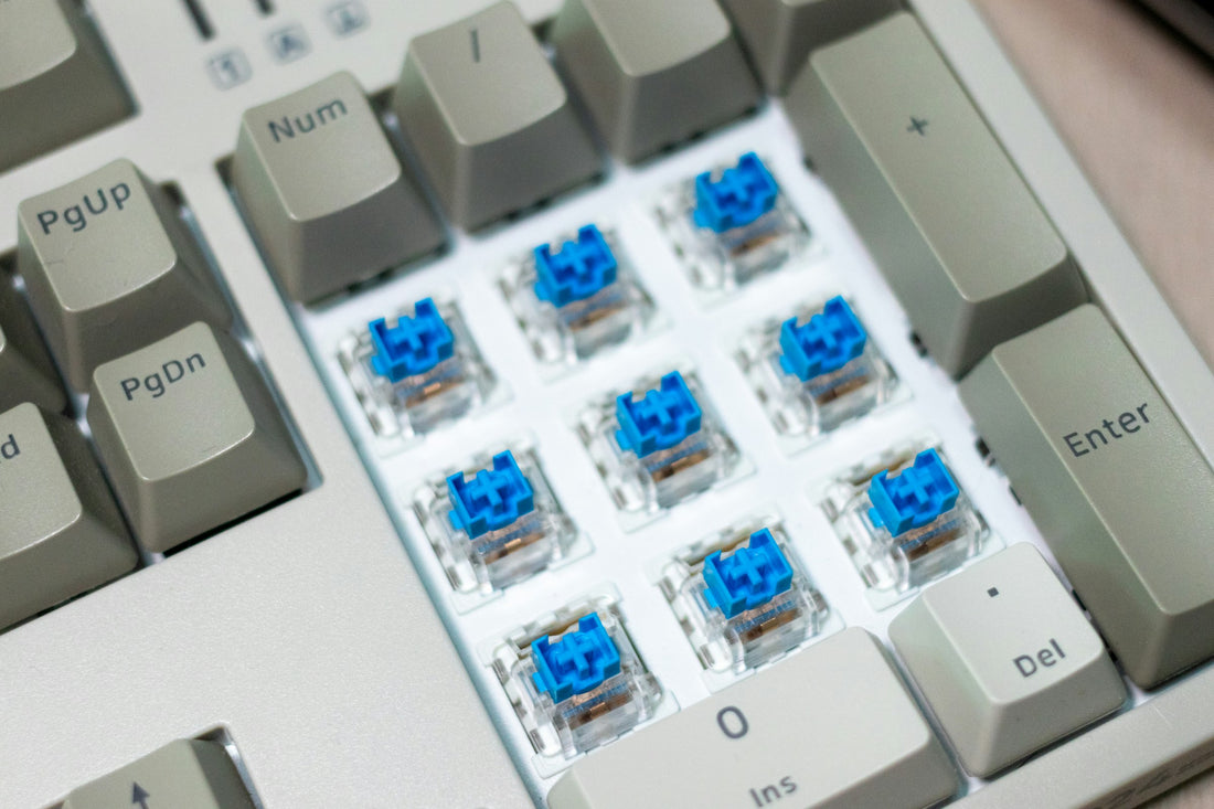 Mechanical keyboard with keycaps removed showing blue switch mechanisms underneath